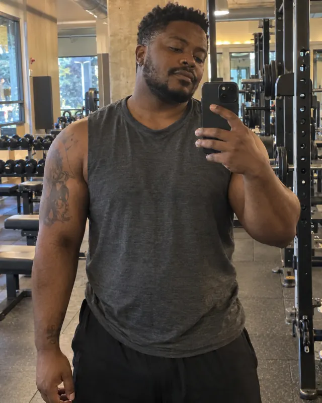 Illustrative adult creator taking a mirror selfie in a gym
